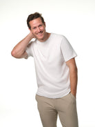 Male model smiling leaning in toward camera wearing our white t-shirt